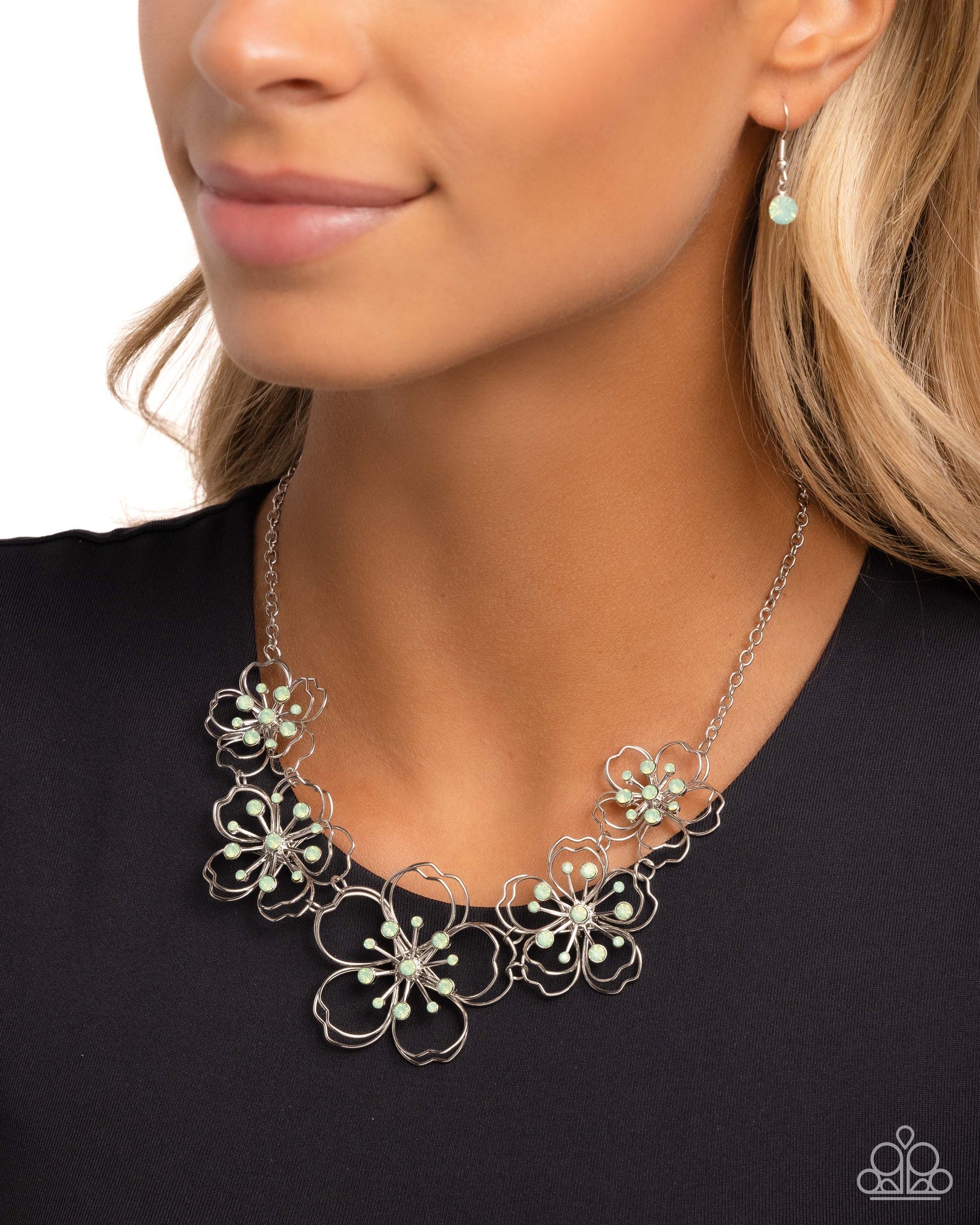 Wiry Wallflowers Green Flower Necklace - Paparazzi Accessories  Shiny silver wire delicately twists into layered blossoms with light green opalescent rhinestone floral centers. Varying in size, the airy floral frames delicately link into an asymmetrical display as the layered frames elegantly pop beneath the collar. Features an adjustable clasp closure.  Sold as one individual necklace. Includes one pair of matching earrings.  P2WH-GRXX-411XX