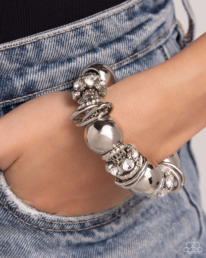 Coiled Confidence White Stretch Bracelet - Paparazzi Accessories  Infused along an industrial abstract stretchy chain, a collection of interlocking silver rings, oversized silver beads, and white gem-encrusted silver accents twists and coils along the wrist for a charismatically confident look.  Sold as one individual bracelet.  P9ED-WTXX-058XX