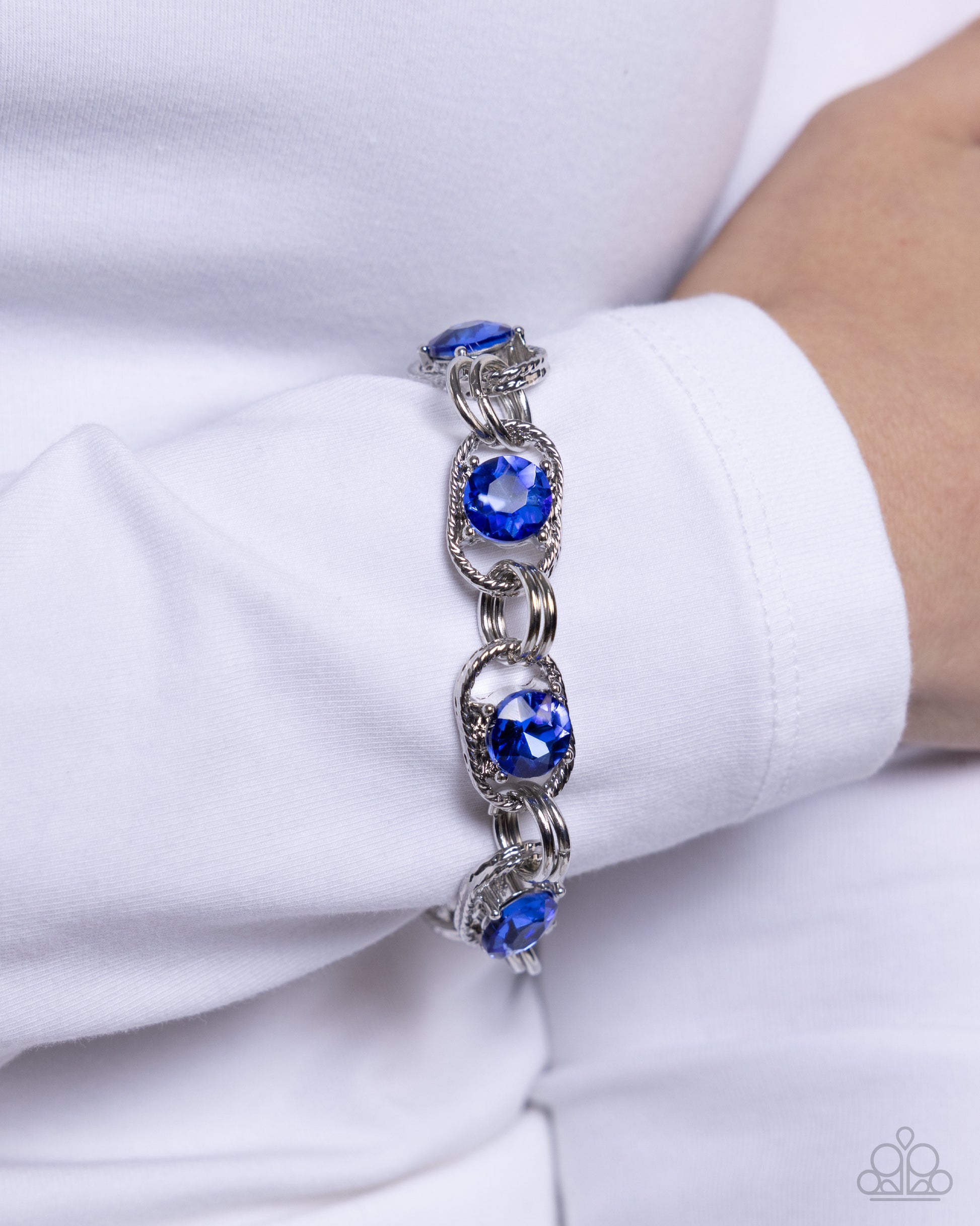 Serrated Secret Blue Rhinestone Clasp Bracelet - Paparazzi Accessories  Set in the center of serrated silver links, a collection of faceted Capri Blue gems link around the wrist by duos of silver rings for a shimmery sensational statement. Features an adjustable clasp closure.  Sold as one individual bracelet.  P9RE-BLXX-256YF