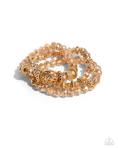 Malibu Maiden Gold Stretch Bracelet - Paparazzi Accessories  Faceted gold clear and opaque beads, various gold beads, and a vintage-embellished oversized bead stack up the wrist on elastic stretchy bands for a classically colorful look.  Sold as one set of three bracelets.  P9BA-GDXX-134XX