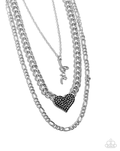 Luxurious Love Black Necklace - Paparazzi Accessories  Three mismatched silver chains loop and layer below the neckline. Featured on the uppermost chain, set in a curly cursive font, silver letters spell out the word "love" while the centermost chain features a black rhinestone-encrusted heart for a romantic radiant display. Features an adjustable clasp closure.  Sold as one individual necklace. Includes one pair of matching earrings.  P2RE-BKXX-488XX