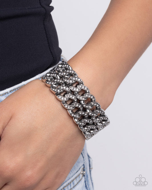 Braided Bandit White Stretch Bracelet - Paparazzi Accessories  Embellished with glistening white rhinestones, elongated silver curb chains stack atop one another to create a bold, stackable braided look along the wrist.  Sold as one individual bracelet.  P9ED-WTXX-060XX