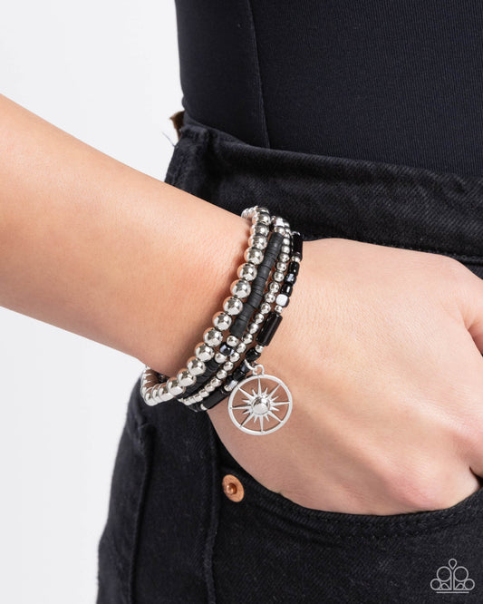 Nuanced Navigator Black Stretch Bracelet - Paparazzi Accessories  Infused along elastic stretchy bands, a collection of black-and-white striped beads, silver, and black beads in varying sizes, black clay discs, and a silver sunburst compass charm swing and stack along the wrist for a noteworthy look.  Sold as one set of four bracelets.  P9BA-BKXX-125XX
