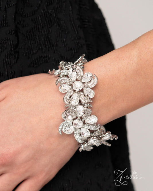 Indulgent Ideal White Rhinestone Stretch Zi Bracelet - Paparazzi Accessories  Item #Z2425  Curls of white rhinestone-embellished silver frames in varying sizes and white teardrop gems bloom around shimmery luminescent round centerpieces into a collection of unique flowers adorned in dizzying, intricate detail. The flourish of florals is threaded whimsically around the wrist on elastic stretchy bands, resulting in an unforgettable statement piece that sparkles with sentiment.  Sold as one individual bracelet