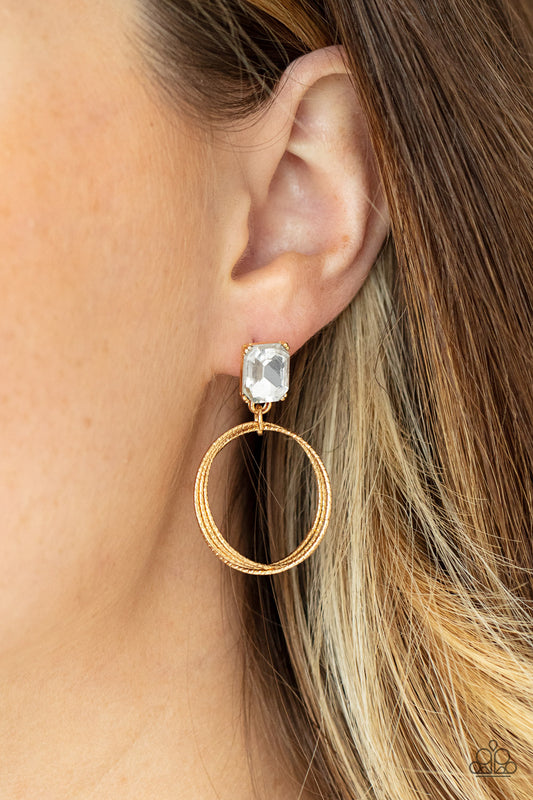 Prismatic Perfection Gold Earring - Paparazzi Accessories  Encased in a pronged gold setting, a white emerald cut rhinestone links with a trio of refined textured gold rings, creating a romantic lure. Earring attaches to a standard post fitting.  All Paparazzi Accessories are lead free and nickel free!  Sold as one pair of post earrings.