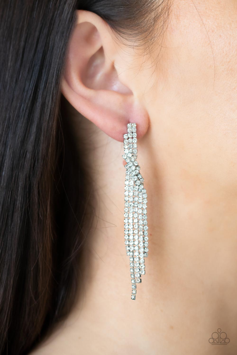 Cosmic Candescence White Earring - Paparazzi Accessories  Encased in sleek silver fittings, dainty strands of glittery white rhinestones delicately overlap into a tapered tassel for a twinkly look. Earring attaches to a standard post fitting.  Sold as one pair of post earrings.