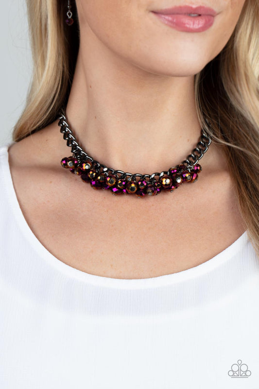 Galactic Knockout Purple Necklace - Paparazzi Accessories  Flecked in oil spill iridescence, a faceted collection of metallic purple beads cluster along the center of a chunky gunmetal curb chain, creating a stellar fringe below the collar. Features an adjustable clasp closure.  Sold as one individual necklace. Includes one pair of matching earrings.