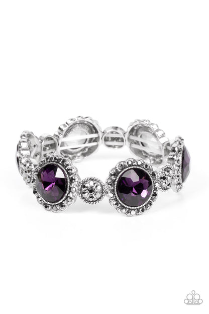 ﻿Palace Property Purple Bracelet - Paparazzi Accessories  An oversized purple rhinestone adorns the center of a hematite rhinestone petaled floral frame. Infused with hematite dotted silver accents, the glitzy floral frames sparkle along stretchy bands around the wrist for a glamorous finish.  Sold as one individual bracelet.