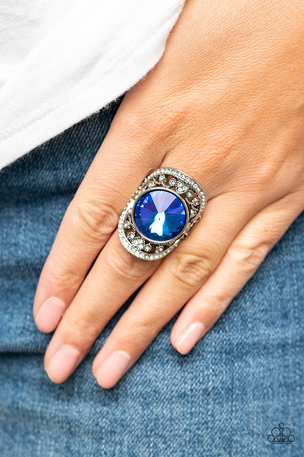 Galactic Garden Blue Ring - Paparazzi Accessories  A dramatically oversized, iridescent blue gem is pressed into the center of an oval silver frame dotted and bordered in glassy white rhinestones, resulting in a sparkly filigree-filled centerpiece atop the finger. Features a stretchy band for a flexible fit. Due to its prismatic palette, color may vary.  Sold as one individual ring.