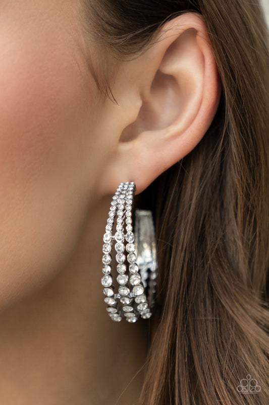 Cosmopolitan Cool White Hoop Earring - Paparazzi Accessories  Cascading layers of sparkling white rhinestones plunge into flattened silver plates creating a stunning eye-catching hoop earring. Earring attaches to a standard post fitting. Hoop measures approximately 2" in diameter.  Sold as one pair of hoop earrings.