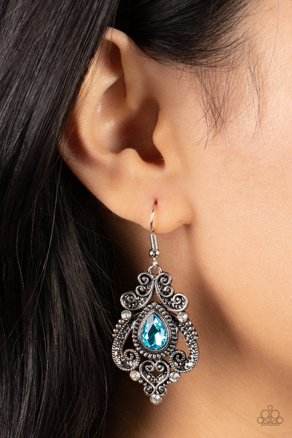 Palace Perfection Blue Earring - Paparazzi Accessories  Dotted with hints of glassy white rhinestones, studded and antiqued silver bars whirl into a regal heart shaped motif around a glittery blue teardrop center for a romantic finish. Earring attaches to a standard fishhook fitting.  Sold as one pair of earrings.