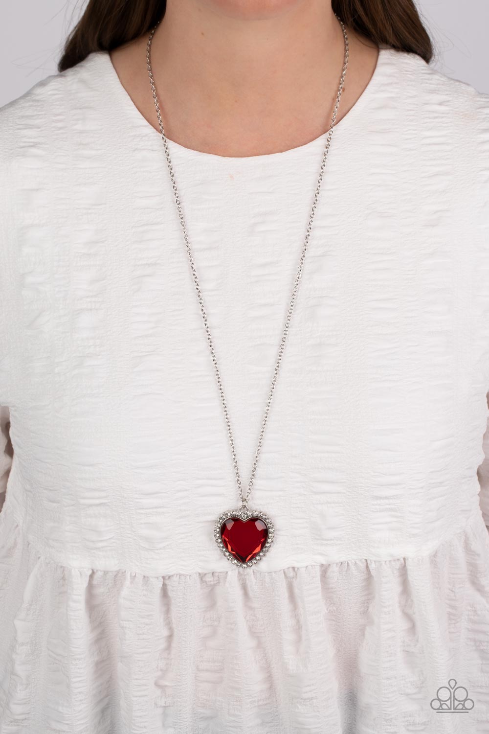 Prismatically Twitterpated Red Necklace - Paparazzi Accessories  Bordered in glassy white rhinestones, an oversized red heart gem sparkles from the bottom of an extended silver chain for a flirty finish. Features an adjustable clasp closure.  Sold as one individual necklace. Includes one pair of matching earrings.