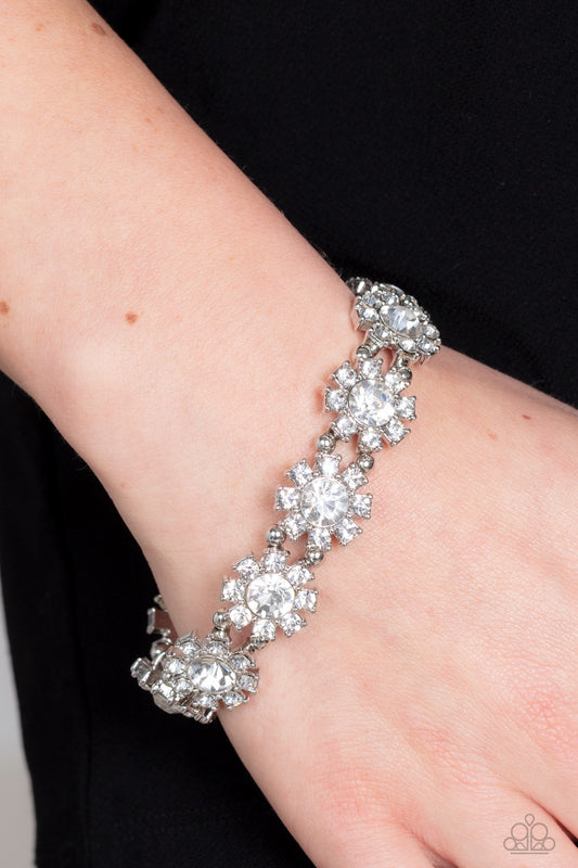 Premium Perennial White Bracelet - Paparazzi Accessories  Separated by pairs of dainty silver beads, rhinestone-dotted petals bloom from oversized white rhinestone centers along stretchy bands around the wrist for a flirtatious floral fashion.  Sold as one individual bracelet.