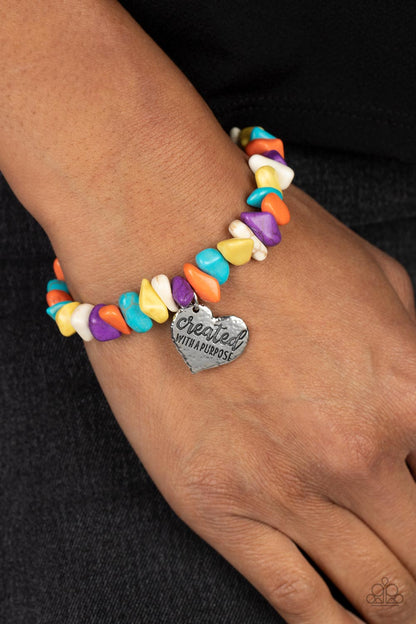 Stony-Hearted Multi Bracelet - Paparazzi Accessories  An assortment of chiseled orange, turquoise, yellow, purple, and white stones are threaded along an elastic stretchy band in a free-spirited pattern. A silver heart charm, hammered in antiqued texture is engraved with the words "created with a purpose" for an inspiring finish. As the stone elements in this piece are natural, some color variation is normal.  Sold as one individual bracelet.