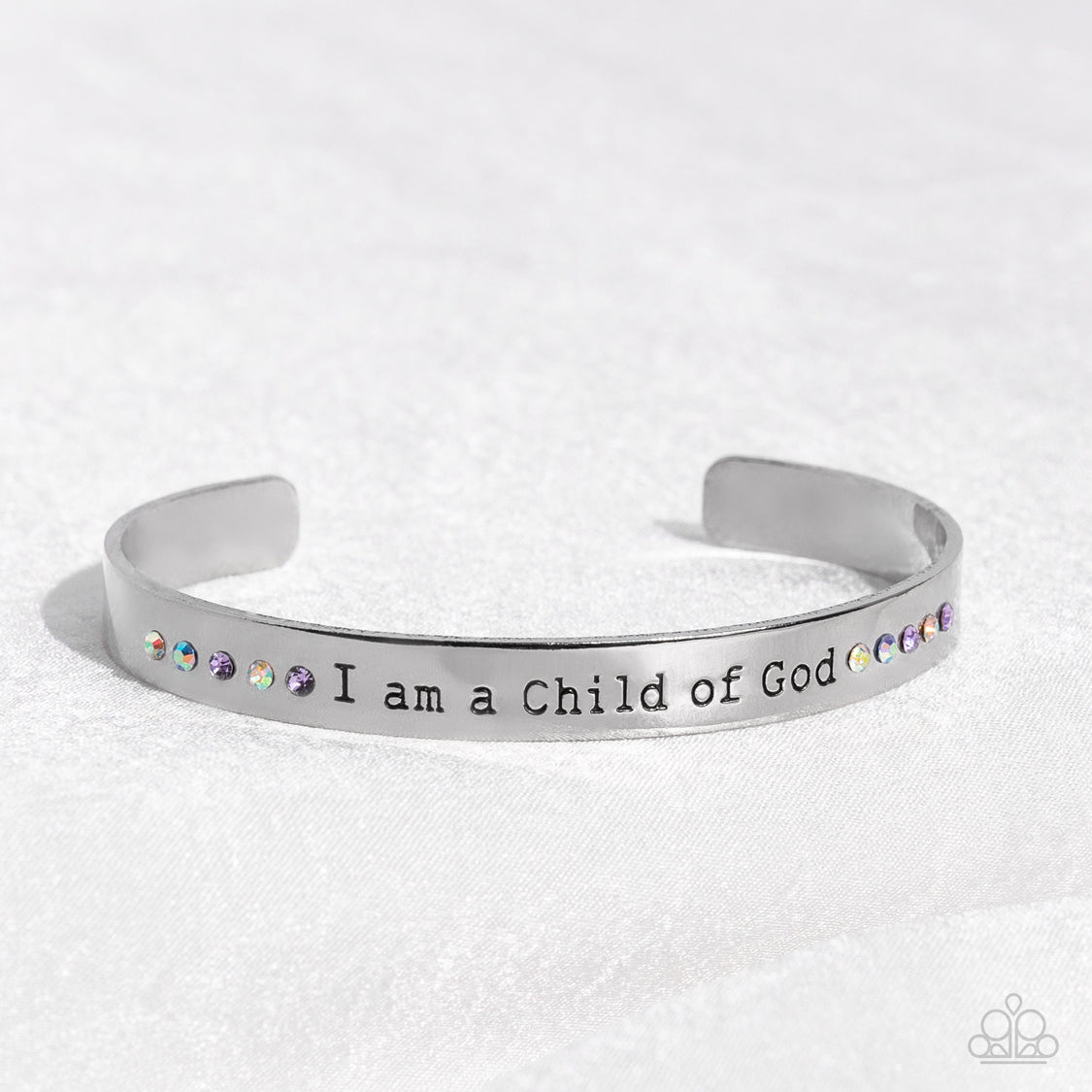 Divine Display Multi Cuff Bracelet - Paparazzi Accessories  A shiny silver cuff stamped with the phrase "I am a Child of God" encircles the wrist. Dainty sapphire, violet and iridescent rhinestones shimmer at the borders of the phrase for a whimsical finish. Due to its prismatic palette, color may vary.  Sold as one individual bracelet.