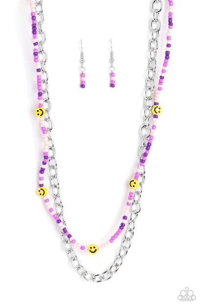 Happy Looks Good on You Purple Necklace - Paparazzi Accessories  Layered together with a bold silver chain, dainty purple, lavender, and baby pink seed beads are paired with yellow smiley face beads that thread along an invisible wire below the collar, resulting in a colorfully retro design. Features an adjustable clasp closure.  Sold as one individual necklace. Includes one pair of matching earrings.