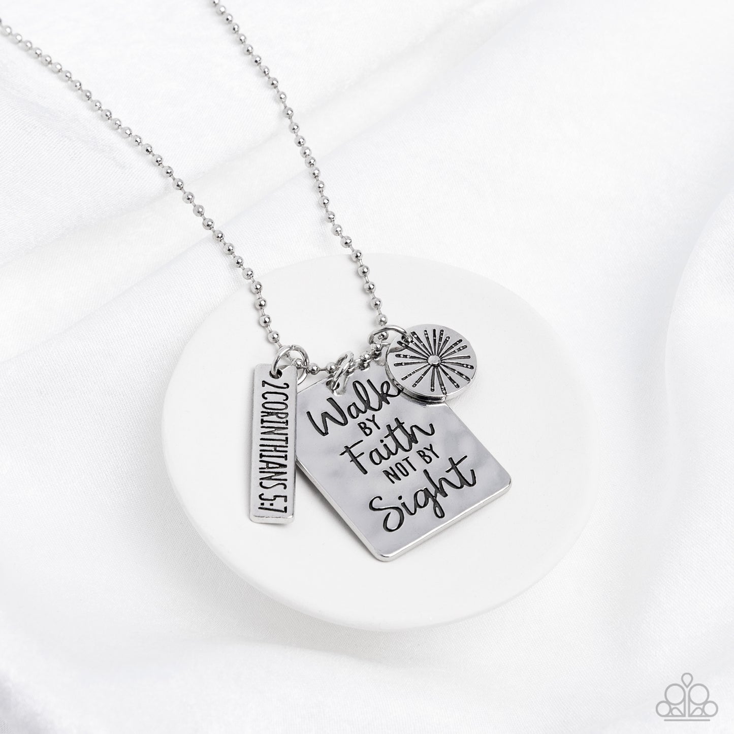 Sunshine Sight Silver Necklace - Paparazzi Accessories  Hanging from a silver ball chain, a hammered collection of a rectangular plate dangles next to a disc featuring a sun, and a bar stamped with the Bible reference "2 Corinthians 5:7". The three dangling silver shapes add eye-catching movement to the inspired design. Prominently stamped on the rectangular pendant, the words "Walk by Faith not by Sight" stand out for a faith-filled finish. Features an adjustable clasp closure.