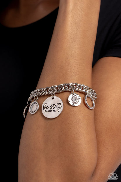 GLITTER and Grace White Inspirational Bracelet - Paparazzi Accessories  Gliding from a thick silver curb chain, a collection of refined charms add some texture and shimmer to this monochromatic mash-up. An oversized, hammered disc is stamped with the phrase "be still" with the scripture reference "Psalm 48:10" listed underneath it. A smaller, hammered disc with a sprinkle of white rhinestones in its center and a silver disc featuring a scalloped ring in its center glide next to the oversized silver disc. 
