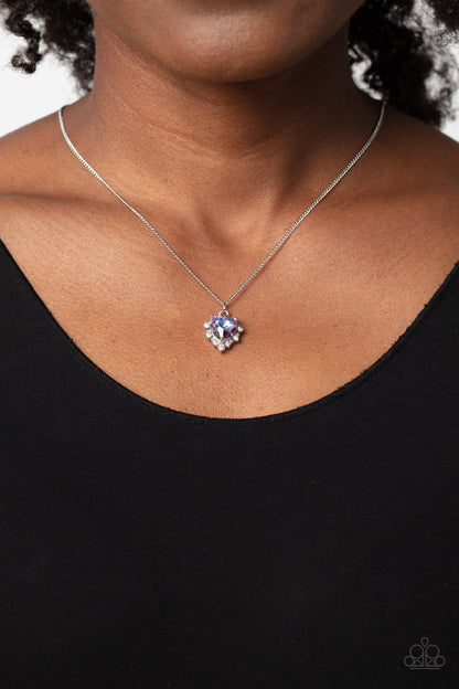 Be Still My Heart Purple Necklace - Paparazzi Accessories  Featuring a subtle UV shimmer, a purple heart gem, pronged in place, glides down the neckline on a dainty silver chain. Bordering the purple heart, a row of dainty white rhinestones creates additional shimmer to the romantic design. Features an adjustable clasp closure. Due to its prismatic palette, color may vary.  Sold as one individual necklace. Includes one pair of matching earrings.  P2DA-PRXX-135XX