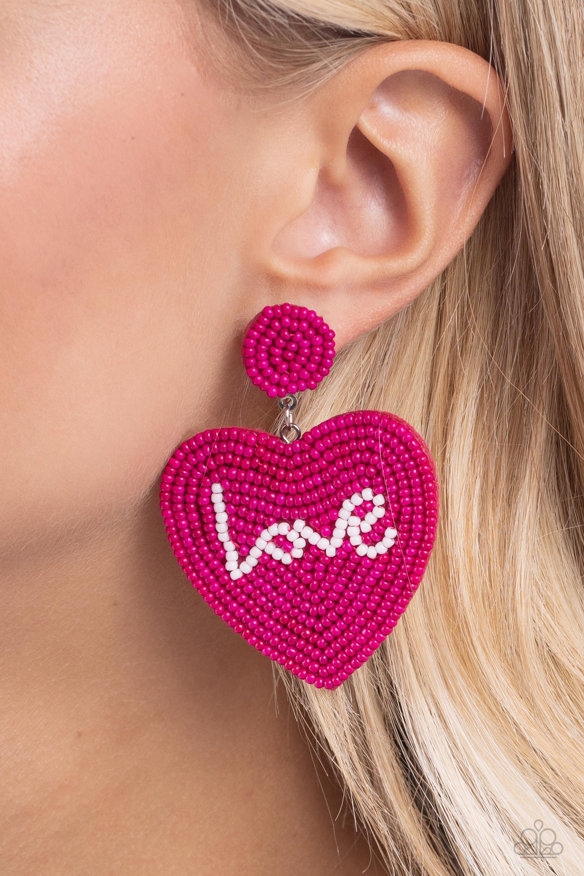 Sweet Seeds Pink Heart Seed Bead Post Earring - Paparazzi Accessories  Hot pink rows of dainty seed beads adorn the front of a heart frame at the bottom of a matching beaded fitting, creating a blissfully beaded look. The word "Love" is spelled out in white seed beads across the center of the heart frame for a romantic finish. Earring attaches to a standard post fitting.  Sold as one pair of post earrings.  SKU: P5PO-PKXX-111XX