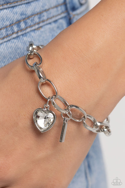 Guess Now Its INITIAL White "I" Bracelet - Paparazzi Accessories  A simple collection of silver charms — including a white rhinestone heart pressed in a silver frame and a sleek letter "I" — dance from a chunky silver chain around the wrist, creating a sentimental fringe. Features an adjustable clasp closure.  Sold as one individual bracelet.  New Kit Sku:  P9BA-WTXX-043XX